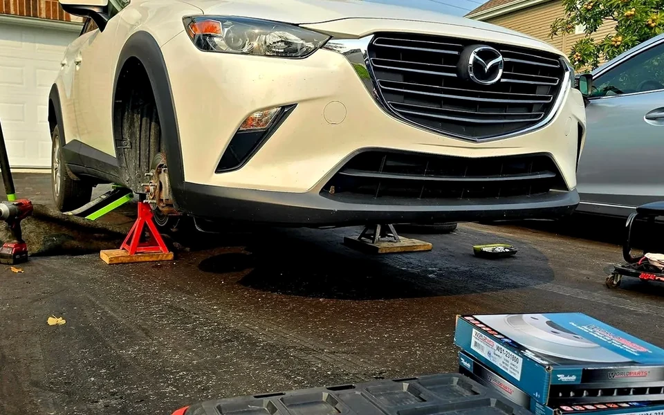 A Mazda with its front wheel removed during a mobile brake service visit